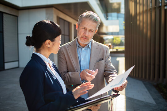 Business colleagues discussing documents outside office