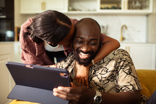 Smiling couple using tablet in home kitchen