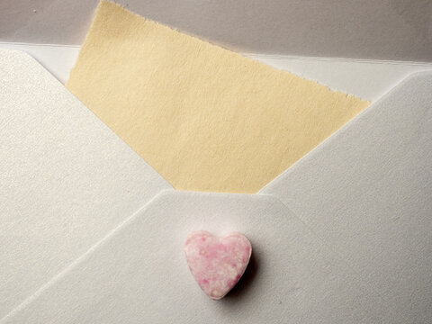 Pink Heart Candy On White Envelope With Torn Yellow Note Suggesting Love Letter