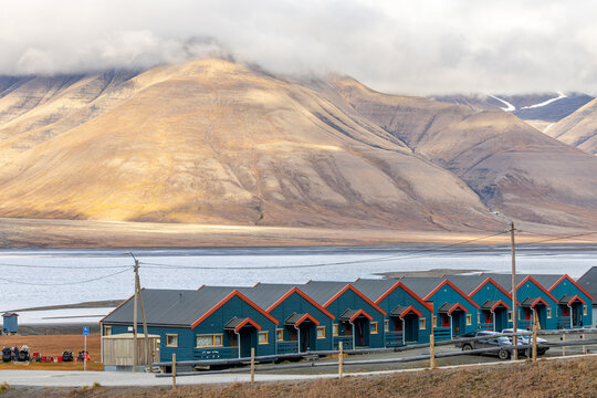 Summer residential view of Longyearbyen with blue wooden houses, calm fjord water and dramatic treeless mountain slopes, Longyearbyen, Spitsbergen, Svalbard, Norway