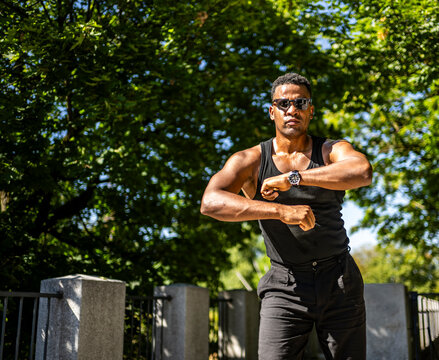 Black male dancer moving to an imagined Latin rhythm outdoors, surrounded by green trees and sunlight, representing cultural expression, music, movement and vitality