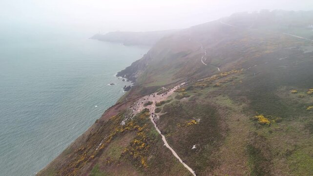 Aerial flight through fog along Howth coast toward the lighthouse