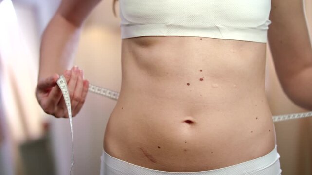 young woman measuring her waist. Woman using measuring tape. checking her body parameters. Diet concept.