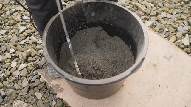 Close up on construction tool mixing mortar or concrete mixture. Preparation for building, renovation or DIY home improvement project outdoors. Industrial and manual labor concept