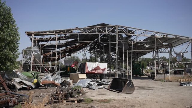 A destroyed agricultural hangar with debris scattered across the farm grounds. Concept hostile shelling.