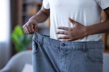 Weight loss success and healthy lifestyle, woman wearing oversized jeans after dieting and fitness progress to show body transformation and wellness achievement
