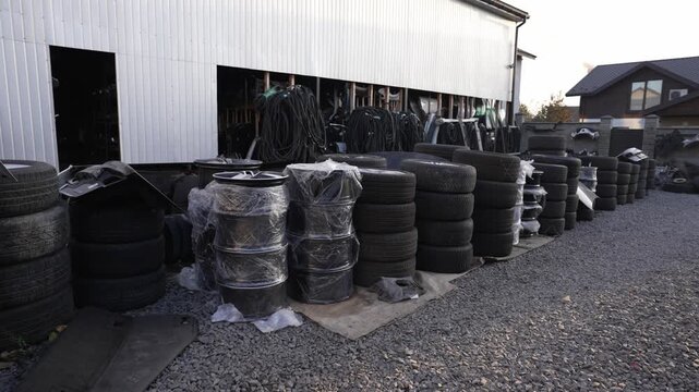 Stacks of car tires and wheel rims wrapped in plastic film are displayed for sale. Auto parts sales concept.