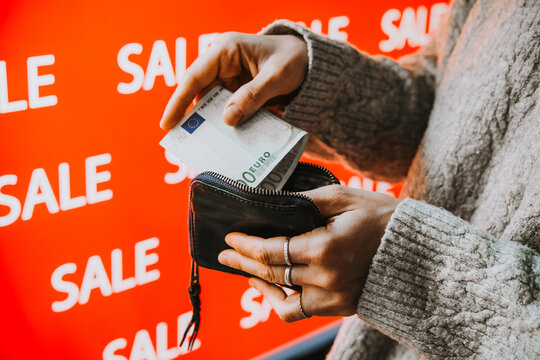 Person taking euro banknotes from wallet during sale shopping.