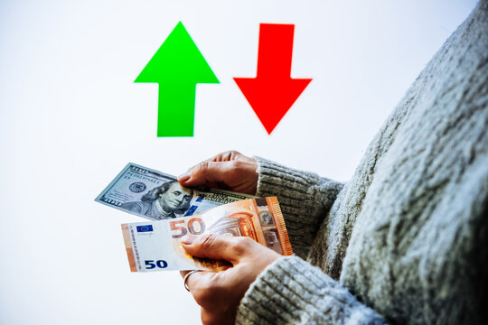 Hands holding U.S. dollars and euros, with contrasting upward and downward arrows.