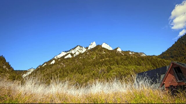 Beautiful view of Three Crowns mountain peak in Pieniny Mountains Poland, scenic autumn landscape with jagged limestone rocks and colorful forest under blue sky.