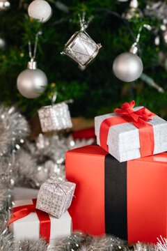 Christmas presents with red ribbon details under a decorated festive tree, celebrating holiday season joy and gift-giving traditions in a bright home setting