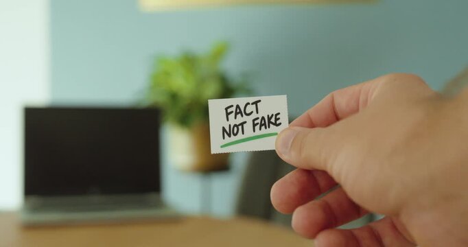 Close-up of a hand holding a &ldquo;Fact Not Fake&rdquo; card, representing factual information, truth, verification and awareness of misinformation.