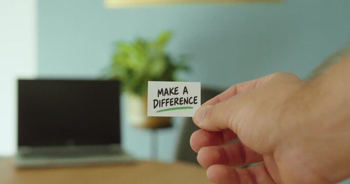 Close-up of a hand holding a &ldquo;Make a Difference&rdquo; card, representing positive change, motivation, impact and personal responsibility.