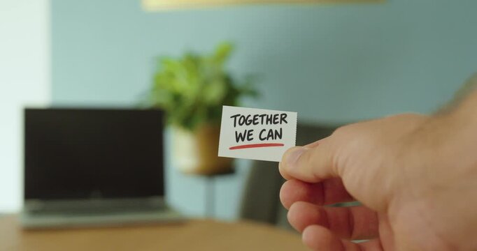 Close-up of a hand holding a &ldquo;Together We Can&rdquo; motivational card, representing teamwork, collaboration, unity and mutual support.
