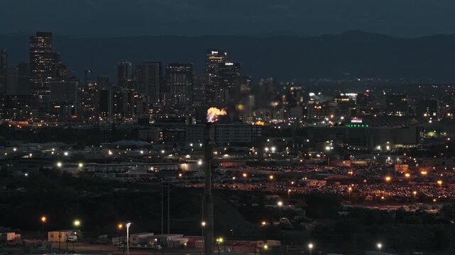 Flaming chimney oil refinery plant industrial zone with city skyline Denver Colorado 4K