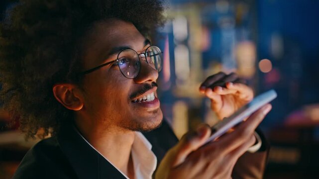Close up man sending voice message phone. Night office worker talking mobile.