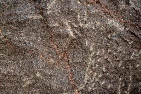 Rough surface texture of natural brown granite stone with mineral veins, cracks, and weathered grain, representing geological solid rock background.