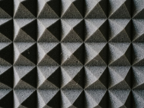 Dark grey acoustic foam panel with pyramid pattern. Soundproof insulation material for audio recording studio wall