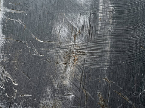 Distressed dark grey anodized aluminum texture. Heavily scratched metallic surface with crosshatch gouges. Rough industrial background