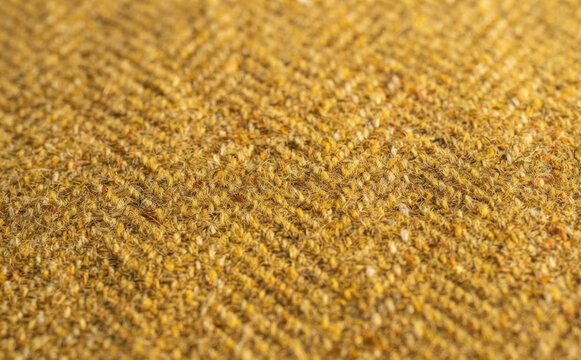 Macro close up of a yellow tweed fabric texture with a woven herringbone pattern for interior design and upholstery background