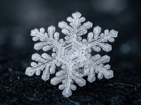 Macro photograph of a single hexagonal snowflake. Close-up of intricate transparent ice crystal on dark textured background. Winter season concept