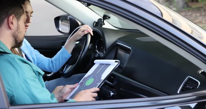 Driving school. Instructor showing student scheme of roundabout in car