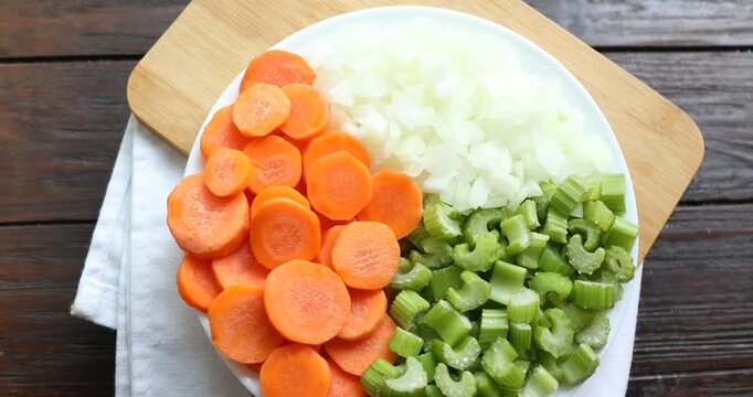 Cut carrots, onions and celery on wooden table, spinning. Top view