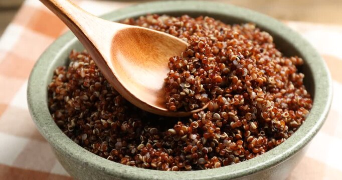 Taking tasty red quinoa with spoon at table, closeup