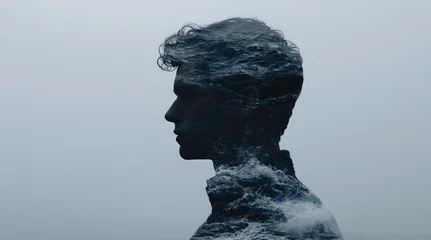 Double exposure side profile of a man blended with ocean waves against a gray background, creating a conceptual portrait with copy space. © oksa_studio