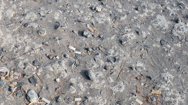 Discarded cigarette butts and scattered debris on a rocky outdoor surface