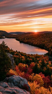 a serene autumn sunset. The sky transitions from deep orange to fiery red, with the sun casting a radiant glow over the horizon.
