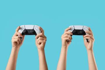 Gaming and esports competition, two people holding modern wireless game controllers for multiplayer video game entertainment on a blue background © Pixel-Shot