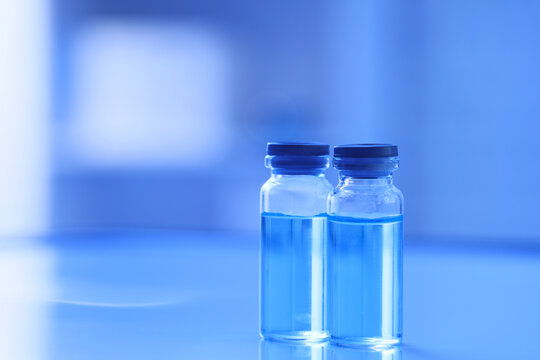 Vaccination and medical research, glass vials with blue liquid for pharmaceutical development and healthcare innovation in a laboratory setting