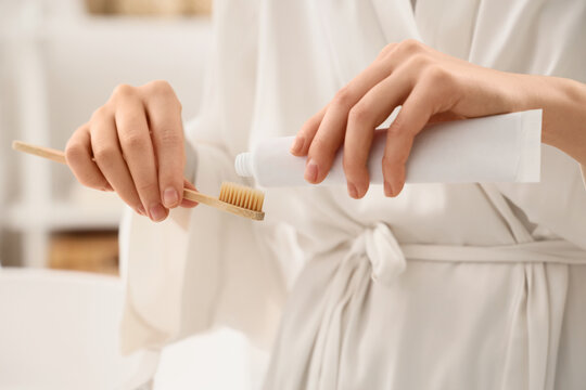 Oral hygiene and sustainable living, woman applying toothpaste on a bamboo toothbrush for daily dental care routine in a bright bathroom environment