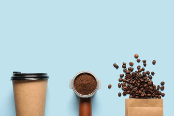 Obraz premium Takeaway cup with coffee bag, beans, portafilter and powder on blue background
