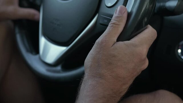 Male driver adjusts controls while holding the steering wheel with his right hand, emphasizing hand movements and vehicle interior details