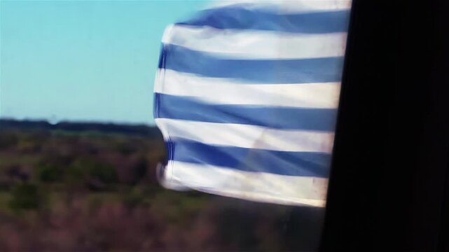 Uruguayan Flag Waving Outside Moving Train Window in Rural Countryside - 4K