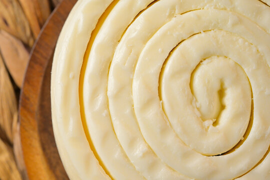 Close-up top view of fresh rolled quesillo cheese spiral on wooden plate