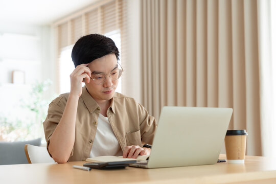Young Asian man working on laptop at home
