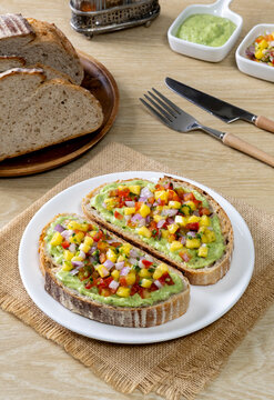 Freshly made salsa served on sourdough bread on a wooden table.