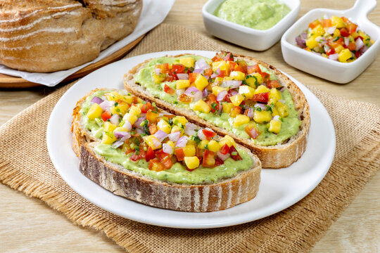 Freshly made salsa served on sourdough bread on a wooden table.