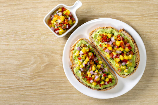 Freshly made salsa served on sourdough bread on a wooden table.