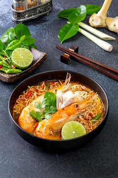 Instant noodles, Tom Yum Goong spicy shrimp soup In a black bowl on a wooden table