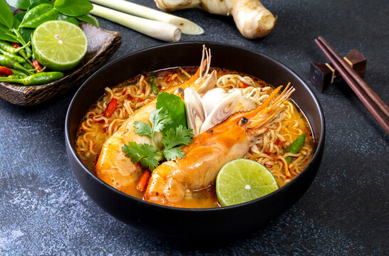 Instant noodles, Tom Yum Goong spicy shrimp soup In a black bowl on a wooden table