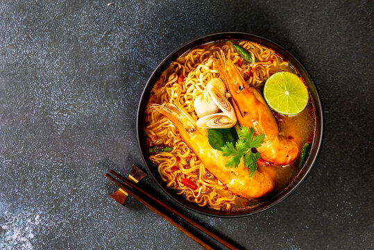Instant noodles, Tom Yum Goong spicy shrimp soup In a black bowl on a wooden table