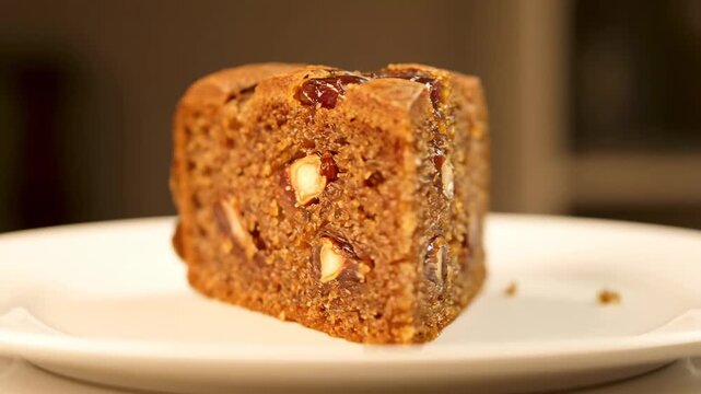 Close-up Slice of Moist Date and Nut Cake or Rich Fruitcake on a White Plate, Showing Dense Texture and Baked-in Ingredients
