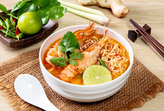 Instant noodles, Tom Yum Goong spicy shrimp soup In a white bowl. on a wooden table