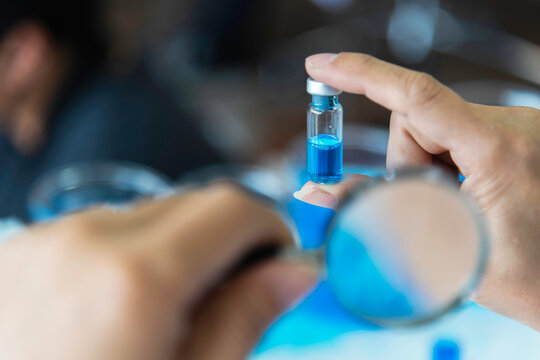 Scientist, or researcher in a laboratory holding a magnifying glass looking .concept study of the virus background