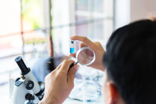 Scientist, or researcher in a laboratory holding a magnifying glass looking .concept study of the virus background