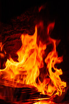 Flames of burning wood flicker inside the fireplace firebox.